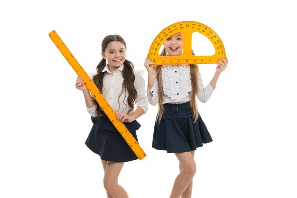 La lección de geometría es muy divertida. Niñas sosteniendo transportador y regla para la lección. Niños pequeños con instrumentos de medición en la clase escolar. Lindas colegialas preparándose para la lección de geometría —  Fotos de Stock