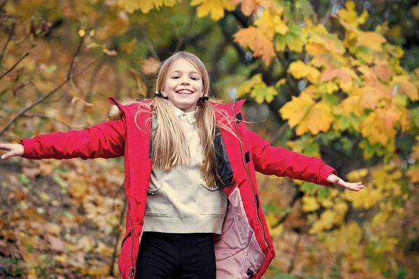 Cutie libre et heureuse. Enfant blond cheveux longs marchant en veste chaude en plein air. Fille heureuse en manteau rouge profiter parc naturel d'automne. Enfant porter manteau à la mode avec capuche. Vêtements d'automne et concept de mode — Photo