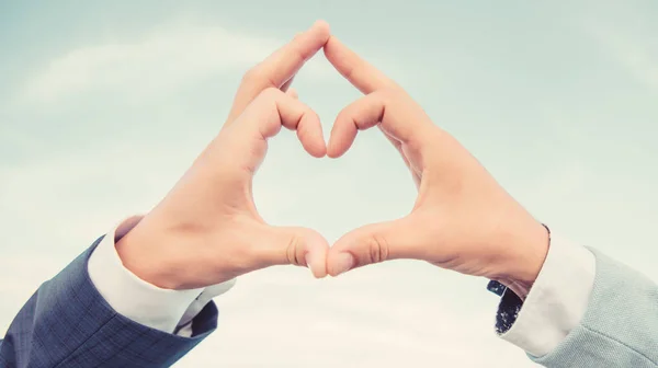 Kéz szív gesztus formák alakja segítségével ujjak. Kezek össze a szív alakú kék ég háttérben. Szerelmi szimbólum koncepció. Férfi kéz a szív alakú gesztus szimbóluma szerelem és romantika — Stock Fotó