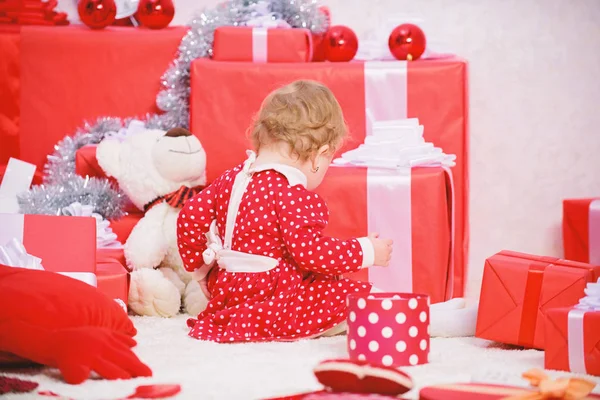 Вещи, связанные с малышами на Рождество. Маленькая девочка играет рядом с кучей подарочных коробок. Семейный праздник. Подарки для первого ребенка. Рождественские мероприятия для малышей. Рождественское чудо — стоковое фото