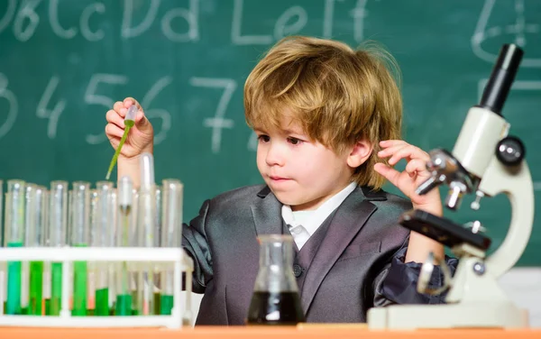 Toddler genius baby. Science concept. Gifted child and wunderkind. Kid study chemistry school lesson. School education. Boy use microscope and test tubes in school classroom. Chemical analysis