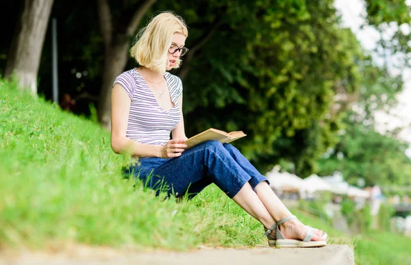 Letteratura per le vacanze estive. Ragazza rilassante sul lungofiume dopo la giornata lavorativa. Riposo relax e hobby. Vacanze estive. Studente nerd intelligente sedersi su erba verde e leggere il libro. Donna che sogna di vacanza — Foto Stock