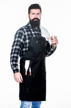Parkta et pişirmek. Sakallı hipster barbekü için önlük giyer. Kavurma ve ızgara yemeği. Adam pişirme gereçleri barbekü tutun. Açık havada et kavurma araçları. Piknik ve barbekü. Barbekü ustası