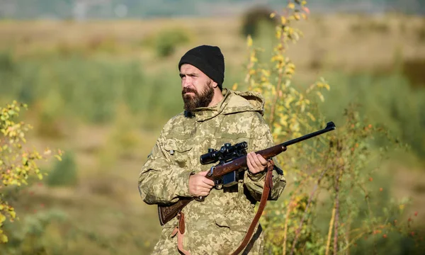 Adam acımasız gamekeeper doğa arka plan. Hunter tüfeği tutuyor. Sakallı avcı boş zamanlarını avlayarak geçirir. Odak ve deneyimli avcı konsantrasyonu. Avcılık ve yakalama mevsimleri. Avcılık erkeksi hobi