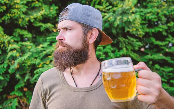 Drinking culture. Hipster holding beer mug. Bearded hipster drinking beer on summer nature. Hipster drinker. Hipster man with craft beer. Brutal man with drinking habits. Drinking only heavy beer