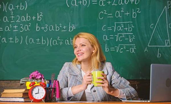 Una mujer bebe café en clase. profesor con despertador en pizarra. El tiempo. De vuelta a la escuela. Día del maestro. Estudio y educación. Escuela moderna. Día del conocimiento. En la escuela. Enseñanza en casa. mujer feliz — Foto de Stock