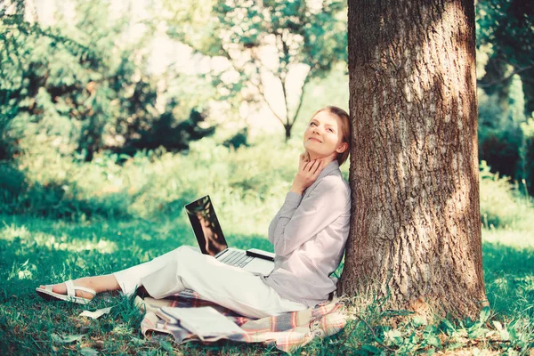 Utbildningsteknik och Internet koncept. Flicka arbeta med laptop i parken sitta på gräs. Natural Environment Office. Arbete utomhus fördelar. Kvinna med laptop arbete utomhus Lean Tree. Minut för avkoppling — Stockfoto