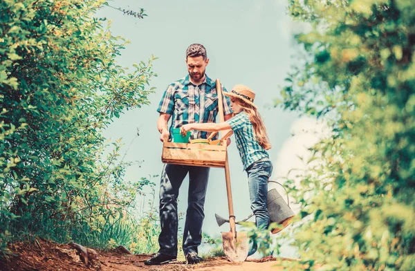 Letní farmaření. farmář s malou holkou. Jaro a léto. lopata a zavlažovací plechovka. Děcko s tátovou skříňkou. rodinné pouto. Vesnice na jarním venkově. otec a dcera na ranči — Stock fotografie