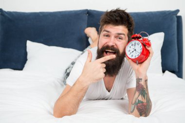 Uyanma zamanı. Neden her sabah erken kalkmalısın? Erken yükselen sağlık yararları. Erken uyanma hazırlamak ve zamanında olmak için daha fazla zaman verir. Hipster sakallı adam çalar saat ile yatakta yatıyordu