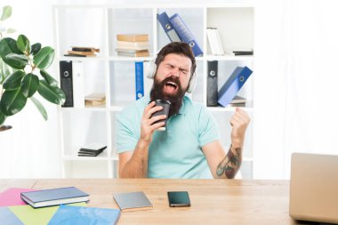İlham verici ve enerji dolu. Ofis yaşam ritmi. Normal ofis günü. Adam sakallı adam kulaklıkofiyer oturup müzik şarkı dinlemek. Kahve fincanı ile Işçi favori şarkı ile iş günü başlar