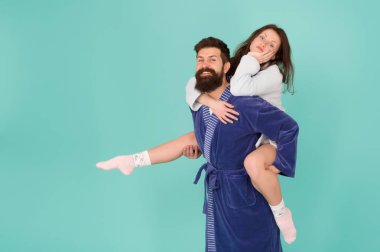 Yakın ilişki. Yakışıklı genç adam kız arkadaşı piggyback binmek veren. Bornozçift eğlenceli turkuaz arka plan sahip. Evde kalıp eğlenelim. Her zaman birlikte eğlenirler.