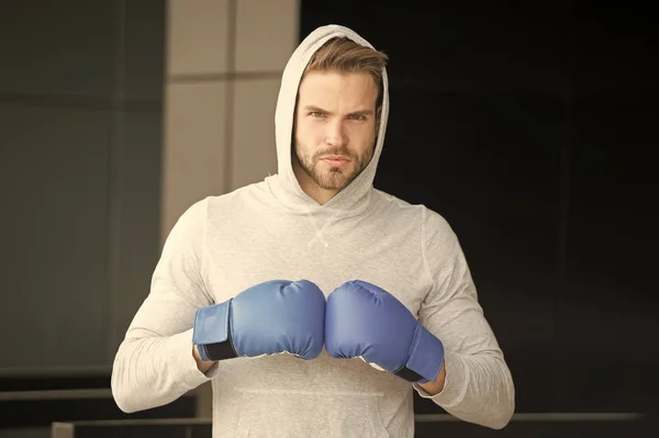 Focused sport goal achievement. Sportsman concentrated training boxing gloves. Athlete concentrated face sport gloves practice fighting skills urban background. Boxer handsome strict coach boxing