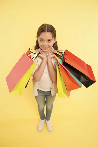 Todo para mí. Niña feliz cara sonriente lleva paquetes de racimo fondo amarillo. Concepto de cumpleañera. A la chica le gusta recibir regalos y regalos de cumpleaños. Niño feliz celebrando cumpleaños con regalos —  Fotos de Stock