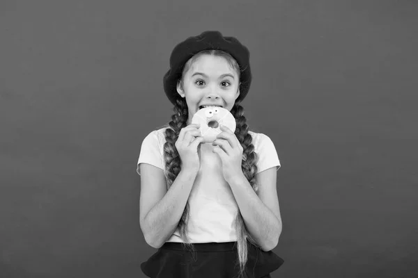 Niña sonriente lista para comer donut. Tienda de dulces y concepto de panadería. Los niños los aficionados enormes de las rosquillas cocidas. Imposible resistirse a la rosquilla fresca. Niña mantenga esmaltado lindo donut en la mano fondo rojo —  Fotos de Stock