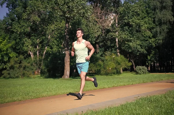 Jeho maximální rychlost. Muž běžec v pozadí park přírody slunečný den. Muž školení, připravit své tělo na maraton. Marathon populární sportovní výzva zlepšit sami. Připojte se ke komunitě ráno jog — Stock fotografie