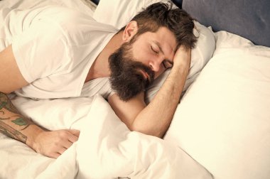 Uyku bozuklukları kavramı. Adam sakallı hippi uyku ile ilgili sorunlar yaşıyorsanız. Yatakta yatan adam rahatla ve uykuya çalışın. Gevşeme teknikleri. Uyku ve uyanıklık ihlali. Biraz dinlenmelisin