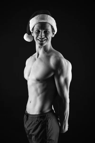 幸せな冬の休日。赤。新年会。サンタ クロースの男。クリスマスの買い物。クリスマスのプレゼント。サンタの帽子でセクシーな筋肉男。彼の適性の政体に自信を持っています。一緒に新しい年を祝う — ストック写真