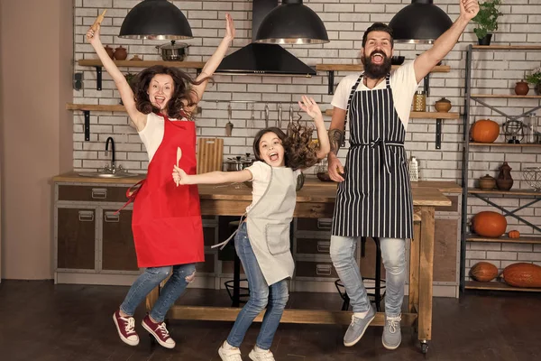 Home party. Happy family jump. Father, mother and child chef cooking. Little girl with parents in apron. Mother and father with little girl. Family day. Happy family in kitchen. Happy family morning