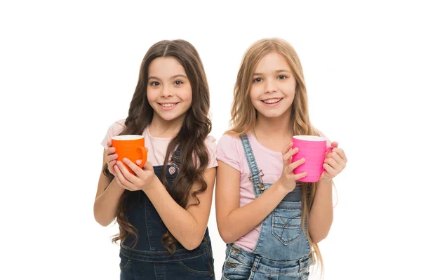 Chicas lindos niños de pelo largo beben cacao o té. Colegialas con tazas de té. Relájate y recarga. Concepto de balance hídrico. Disfrutando del té juntos. Hermanas o amigos beben agua. Más energía —  Fotos de Stock