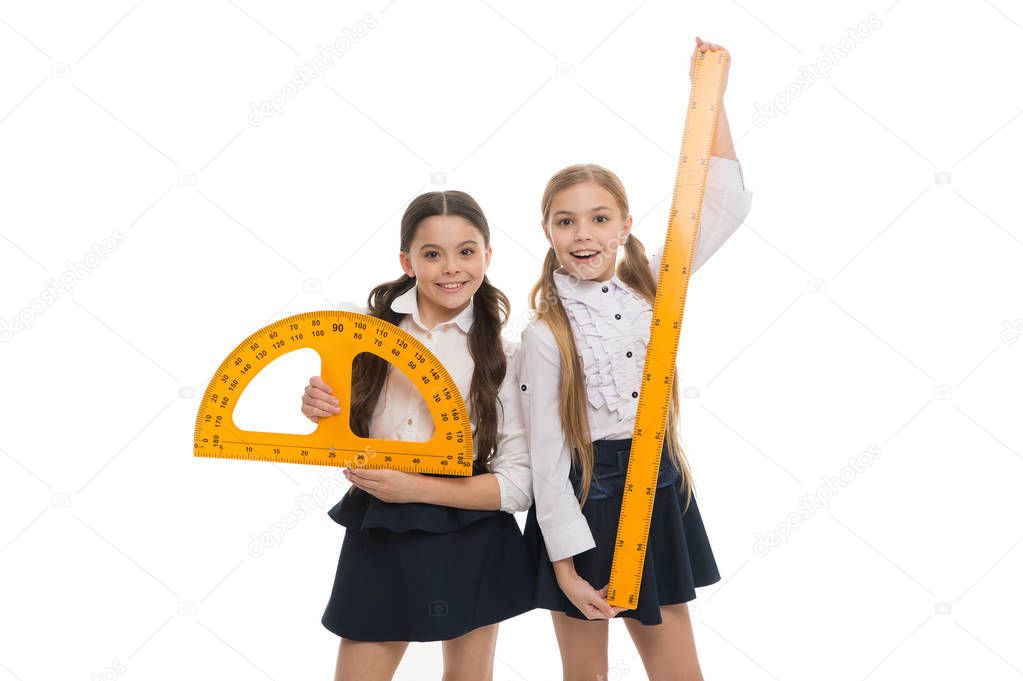 Being ready for lesson. Cute schoolgirls holding protractor and ruler for lesson. Little girls preparing for geometry lesson. Small children with measuring instruments at school lesson