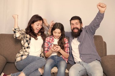 Aile birlikte hafta sonu geçirmek. Küçük kız kullanma smartphone ile çocuk anne. Dostu aile birlikte eğleniyor. Anne baba ve meşgul kızı kanepede rahatlatıcı. Aile eğlence. Ebeveyn tavsiyesi