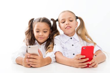 Modern öğrenciler. Sınıfta cep telefonu kullanan küçük öğrenciler beyaz üzerine izole edildi. Küçük öğrenciler ders sırasında mesaj atarlar. Sevimli lyceum öğrenciler akıllı telefon dersleri derin dalış