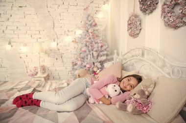 Ev dünyanın en iyi yerdir. Kız küçük çocuk Noel süslemeleri ile yatak ışık iç rahatlatıcı. Noel arifesi kavramı. Çocuk Noel yatak odasında bekliyor. Çocuk yatak rahatlatıcı yatıyordu