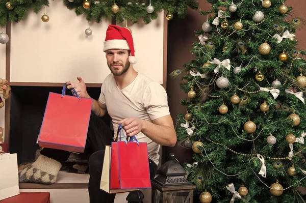 På morgonen innan Xmas. mannen i santa hatt hålla julklapp. Online julhandeln. Nytt år scen med träd och gåvor. santa lycklig. leverans julklappar. Vinter semester försäljning — Stockfoto