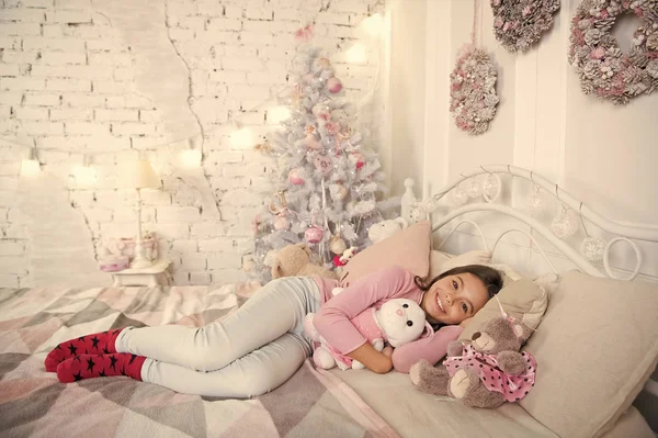 Ev dünyanın en iyi yerdir. Kız küçük çocuk Noel süslemeleri ile yatak ışık iç rahatlatıcı. Noel arifesi kavramı. Çocuk Noel yatak odasında bekliyor. Çocuk yatak rahatlatıcı yatıyordu