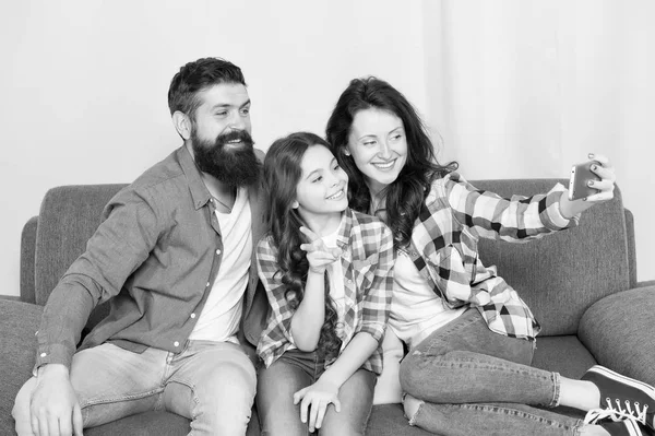 Captura momentos felices. Selfie familiar. La familia pasa el fin de semana juntos. Utilice el teléfono inteligente para selfie. Familia amigable divirtiéndose juntos. Mamá papá y su hija se relajan en el sofá. Familia posando para la foto — Foto de Stock