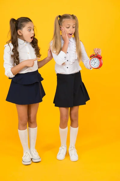 Tijd voor pauze en ontspanning. Het alarm gaat af. Tijd voor de lunch. Schoolrooster. Schoolmeisjes en wekker. Kinderen scholieren schattig formeel uniform outfit. Kinderen houden wekker tellen tijd — Stockfoto