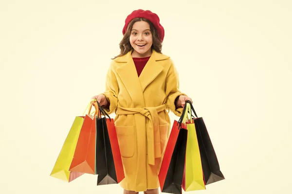 Dívka drží nákupní tašky. Model s dlouhými vlasy na bílém pozadí. Nošení dítěte představuje v papírových taškách. Malý shopaholic s nákupní tašky. Módní trend a prodejní koncept. Nakupování online — Stock fotografie