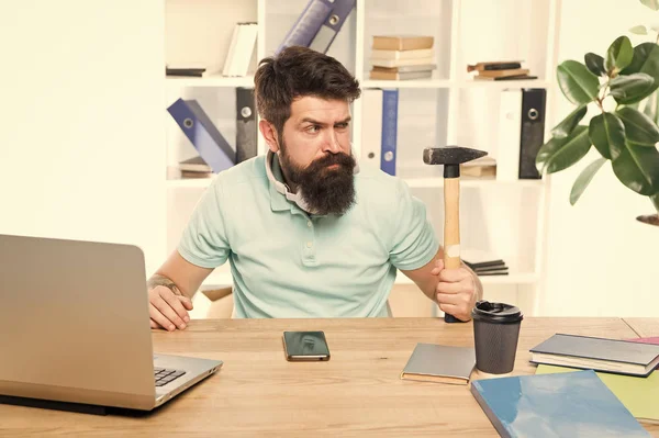 Office life makes him crazy. Businessman with beard and mustache gone mad with hammer in a hand. Angry aggressive businessman in office. Frustrated office worker holding hammer poised ready to smash