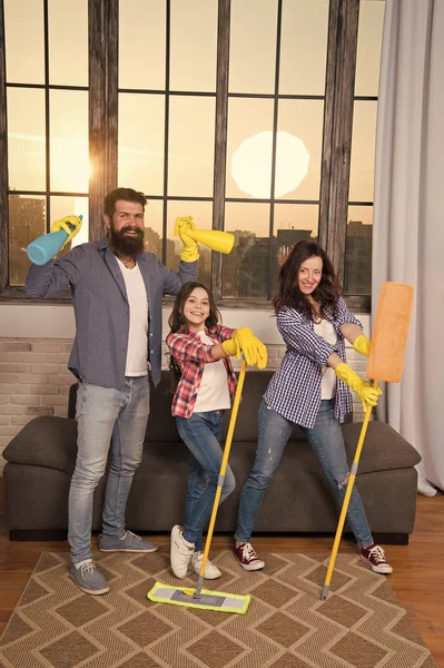 Familia mamá papá e hija con artículos de limpieza en la sala de estar. Nos encanta la limpieza y el orden. Limpiar juntos más fácil y más divertido. El cuidado familiar sobre la limpieza. Comienza a limpiar. Día de limpieza — Foto de Stock