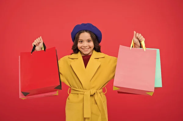 Získejte velkou skříň refresh s jarní prodej v obchodech. Roztomilé dítě dívka drží nákupní tašky červené pozadí. Získejte slevu nakupování na dovolené narozeniny. Fashionista zbožňují, nakupování. Posedlý nakupování — Stock fotografie