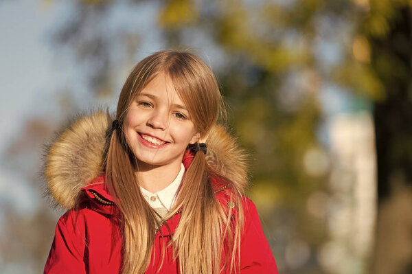 Good mood at fall weather. Kid girl wear coat for fall season. Child cheerful walking wearing warm bright coat or jacket fall sunny day. Girl smiling face fashionable fall coat with hood and fur