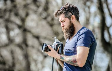 Modern blogcu. İçerik oluşturucu. Adam sakallı hipster fotoğrafçısı. Sakallı ve bıyıklı fotoğrafçı. Uzun sakallı, fotoğraf çeken adam. Manuel ayarlar. Fotoğrafçı tutun vintage kamera