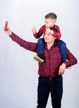 Çocuğun babası olmanın mutluluğu. Eğleniyor. Babalar günü. Asil bir insanın baba örneği. Baba küçük oğlu kırmızı gömlek aile kıyafeti bakmak. Oğluyla selfie çekmek. Babaların omuzlarına binen çocuk