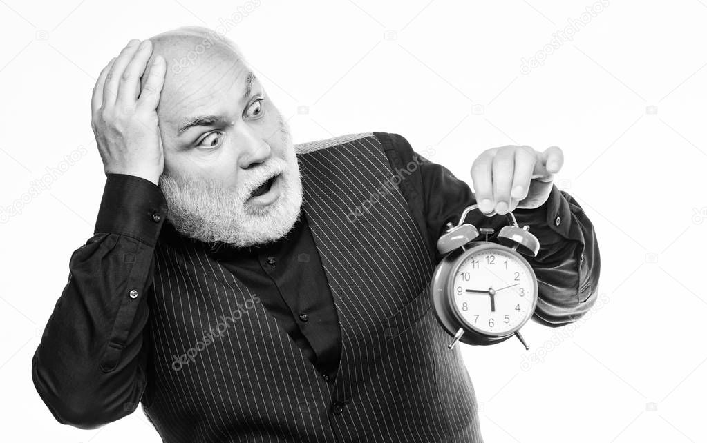 late again. mature bearded man with alarm clock. mature man with beard clock show time. time management. business startup. retirement. watchmaker or watch repairer. time and age. Timekeeping