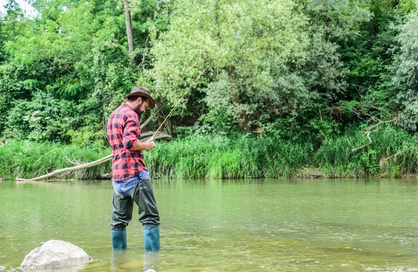 Fisherman alone stand in river water. Man bearded fisherman. Fisherman fishing equipment. Hobby sport activity. River lake lagoon pond. Trout farm. Fish farming pisciculture raising fish commercially — Stock Photo, Image