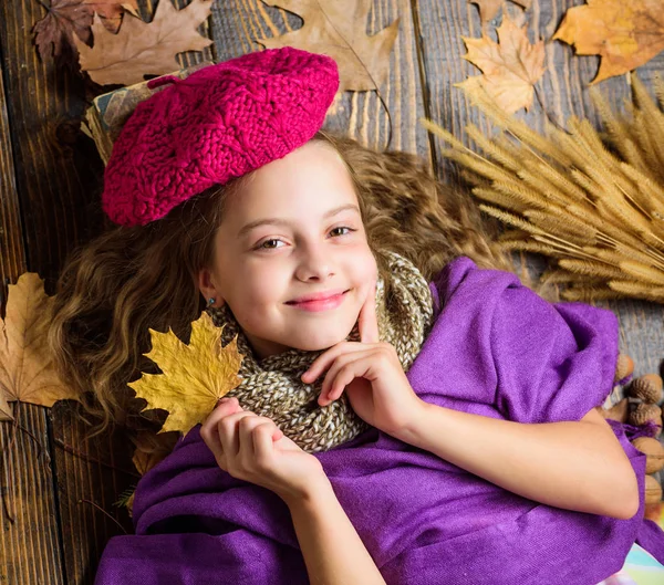 Mode Hut Trend Herbst-Saison. Mädchen niedliches Kind in Strickmütze lag hölzernen Hintergrund gefallen Ahorn Blätter Draufsicht. Herbst Mode Hut Accessoire. Kind Mädchen helle weiche Strickmütze genießen Herbst — Stockfoto