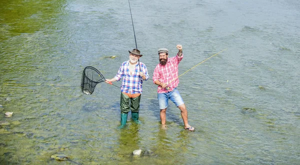 釣りチーム男性の友情父と息子の釣り夏の週末。一緒に釣り。男は水の中に立つ。ナイスキャッチコンセプト。釣り竿と網で幸せな漁師。趣味とスポーツ活動 — ストック写真