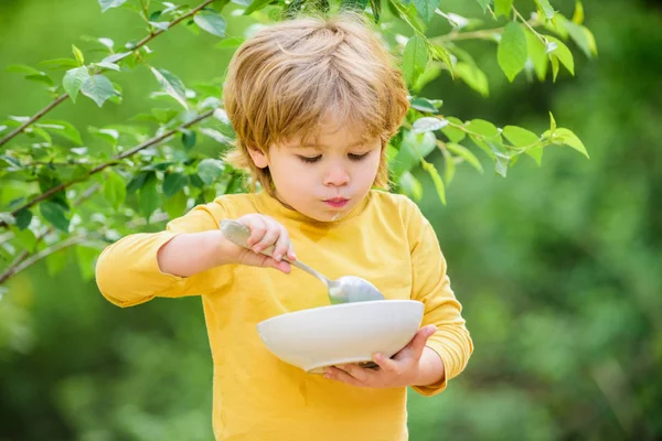 Menino come comida saudável. felicidade infantil. alimentos saudáveis e dieta. Dia da família. filho e comer mingau de leite. cereais ao pequeno-almoço. Bom dia. pequeno menino comendo ao ar livre. Desenvolvimento infantil — Fotografia de Stock