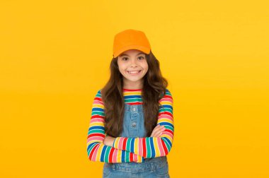 Modaya uygun ve süslü. Aksesuarı olmalı. Modern moda. Çocuk modası. Yaz güneşi koruma şapkası. Kız uzun kıvırcık saç şapka giymek. Sevimli çocuk şapka veya snapback şapka giymek. Beysbol şapkası takan küçük kız