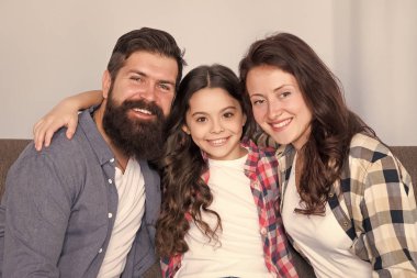 Dost canlısı aile fotoğraf aile albümü için poz kanepede oturup. Anne baba ve kızı kanepede rahatlatıcı gülümsüyor. Aile bağları kavramı. Tek çocuklu tipik bir aile. Aile hafta sonunu birlikte geçiriyor