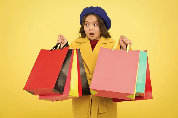 Posedlý nakupování. Roztomilé dítě dívka drží nákupní tašky na žlutém podkladu. Polovina sezóny prodej. Obchod s slevovou kartu. Získejte slevu nakupování na narozeniny nebo svátek. Fashionista zbožňují, nakupování — Stock fotografie