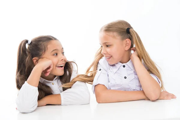 Haciendo nuevos amigos en la escuela. Felices amiguitos hablando durante la clase. Pequeños amigos de la escuela sonriendo el uno al otro aislados en blanco. Adorable chica amigos disfrutando de buenas relaciones de amistad — Foto de Stock