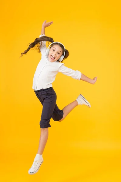 La meilleure danseuse. Adorable petit danseur se déplaçant vers la musique jouant dans les écouteurs. Petite danseuse effectuant un saut de ballet sur fond jaune. Mignonne fille danseuse dansant de retour à l'école danse — Photo