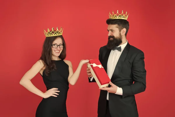 Reina de su corazón. Hombre barbudo rey en esmoquin corona de oro dando caja de regalo a la mujer vestido elegante. Familia real. Pareja enamorada de la familia real. Sociedad de élite. Rey y reina evento formal. Regalo real — Foto de Stock