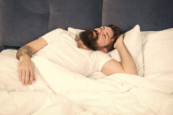 Man bearded hipster having problems with sleep. Guy lying in bed try to relax and fall asleep. Relaxation techniques. Violations of sleep and wakefulness. Sleepless night. Sleep disorders concept